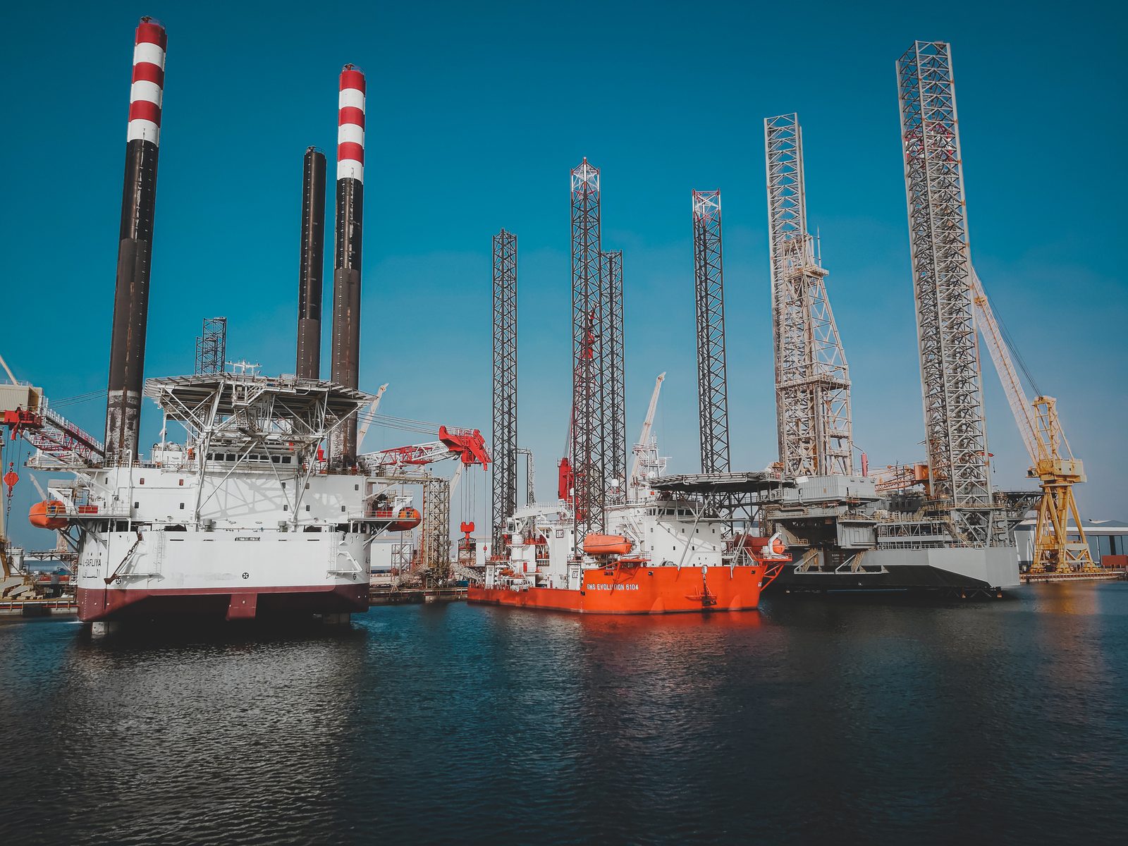 Drilling ships and jack-up rigs docked at port